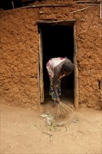 Woman brushing her house with a brush made of dried grass