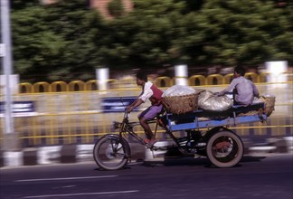 People journeying on a tricycle on the beach road in Chennai