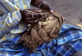 A man carving Ganesha on the shell of coconut