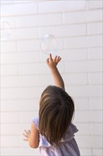 A three year old girl chasing soap bubbles