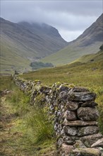 Old dry stone wall in moorland leading to the mountain Bidean nam Bian and the famous Three Sisters of Glen Coe