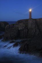 View of coastal cliffs with lighthouse at night