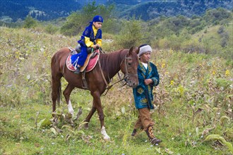 Kazakh man walking around on a horse with his son after the circumcision Sundet Toi ceremony