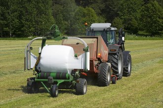 Tractor-drawn baler and mechanical bale wrapper with plastic-wrapped silage round bales