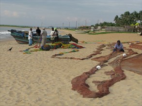 Repairing fishing nets on Negombo beach Sri Lanka