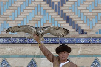 Kazakh man in traditional dress showing his eurasian eagle-owl