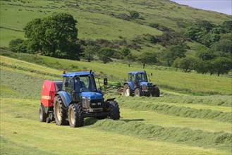 Tractors rowing and baling hay in the field