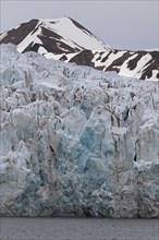 Crumbling ice wall of Nordenskioeldbreen glacier ending in Adolfsbukta