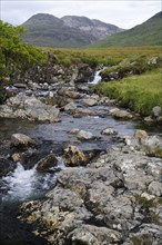 View of burn flowing from mountain towards sea loch