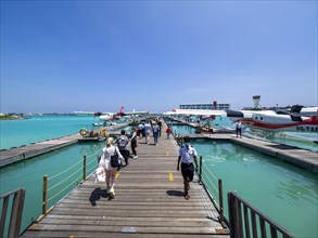 Tourists board pontoon with seaplanes