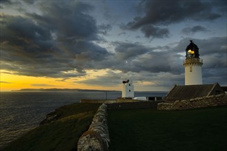 View of clifftop lighthouse at sunset