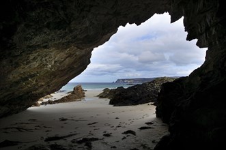 View of beach from inside rocky cave mouth