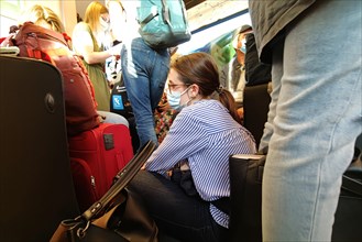 Very many people sitting and standing overcrowded in a local train