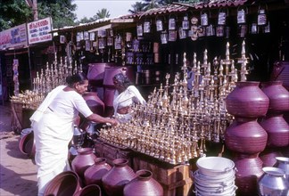 An old women purchasing brass oil lamps in a shop in Ernakulam