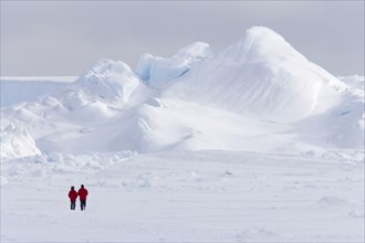 Two tourists walking on the ice of the frozen sea