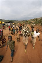 Boys carrying firewood on heads walk along the dusty village road