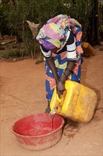 Woman filling bowl with water from a well