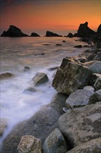 View of the waves on the rocky beach at sunset