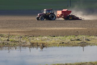 Case 5150 Tractor with Overum seeder sowing a field on the edge of a small river