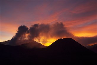 Smoke rising from volcano at sunset