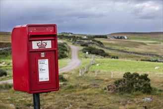 Traditional red Royal Mail letterbox in the bleak landscape at Coigach