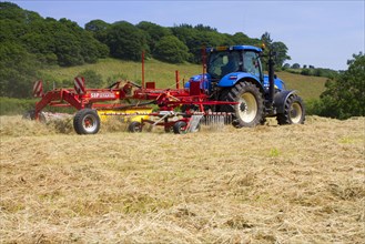 Contractor with New Holland T7030 tractor and SIP hay tedder
