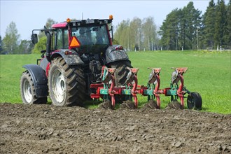 Valtra tractor ploughs field with four-furrow reversible plough