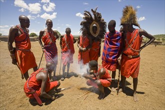 Maasai tribesmen light fire at the edge of the village