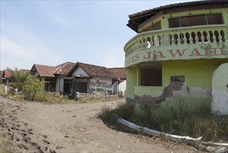 Abandoned village in dried mud after mud volcano flooded by mud lake