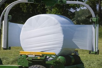 Plastic wrapping round silage bales with mechanical bale wrapper