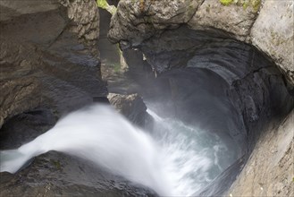 Glacier waterfall flowing over eroded rocks inside mountain