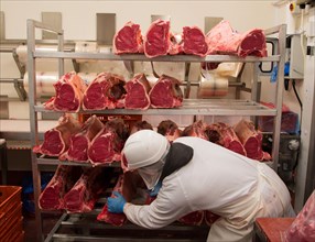 Worker with sirloin joints of beef in abattoir