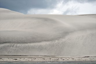 View of coastal sand dunes and beach at edge of lagoon
