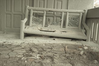 Ash-covered seat outside the house damaged by the recent volcanic eruption