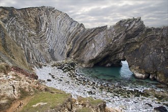 Geological rock formations with rock folding and archways cut into softer rocks of the bay
