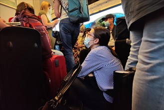 Very many people sitting and standing overcrowded in a local train