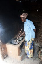Woman preparing food at the cooker in a hut