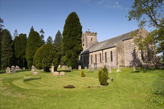 View of headstones and yew trees in churchyard of parish church