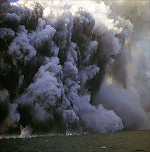 Volcanic island eruption throwing up ash and smoke