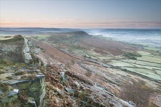View of cliffs and moorland across valley in frost at sunrise