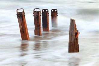 Old wooden groynes with incoming tide at dusk