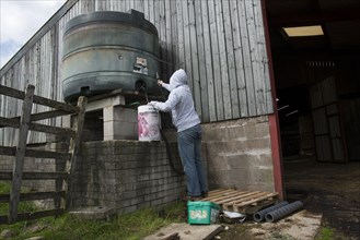 Man in hoodie about to steal diesel from tank on farm