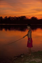 Young fishing in the lake at sunset