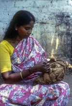 A woman carving on the shell of coconut