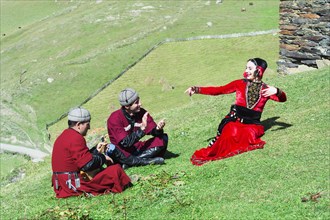 Georgian people from a folkloric group playing panduri and dancing in traditional Georgian dress