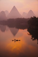 Traditional fisherman standing on a bamboo raft at sunrise