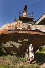 Rusting hulk of old ferry on river bank