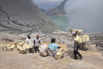 Local man with sulphur blocks in baskets resting on the path around the volcanic crater