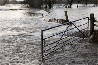 Flooded farmland with gate and damaged fence