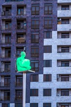Illuminated human sculpture on a pole in front of a building seen from the Yerevan Cascade